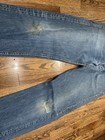 Vintage Levi’s 501XX blue made in USA 80s jeans with frayed front seam and small white tear repair patch on right thigh.