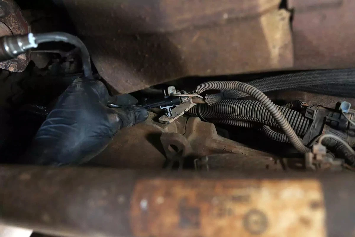 A mechanic secures the oxygen sensor’s plug to the plug mount.