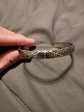This is a silver cuff bracelet with an intricate tribal or geometric design.