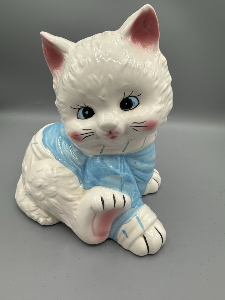 A big-eyed, blue-bow ceramic kitty coin bank with genuine vintage charm — the kind of piece that looks great on a shelf and sparks instant conversation.