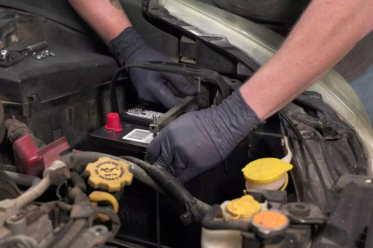 Battery in an engine bay with a top clamp placed over it.