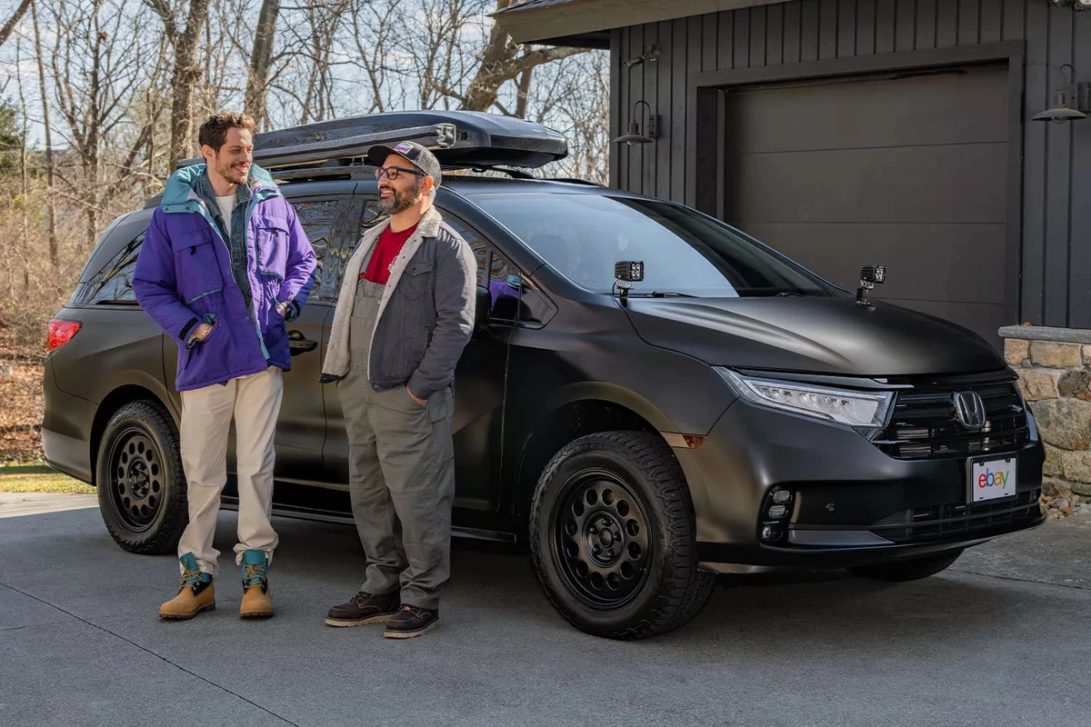 Actor and comedian Pete Davidson stands with car customizer Tony Angelo in front of a modified minivan.
