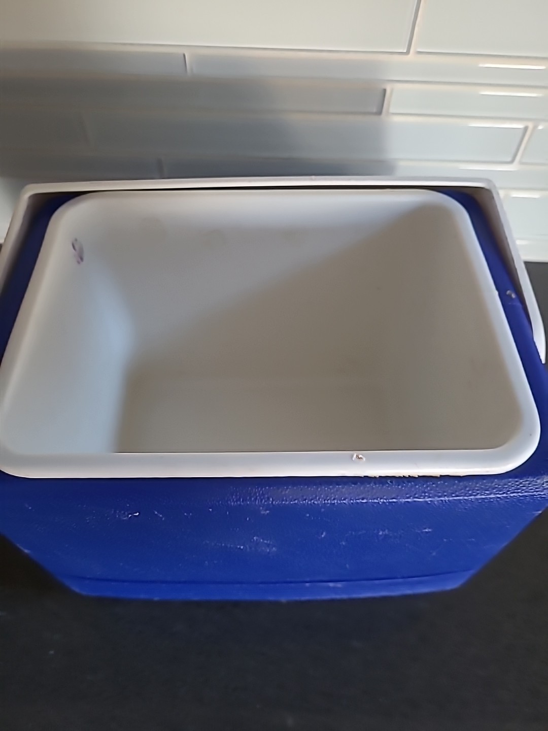 Blue Igloo Playmate cooler with white square lid, side pockets, and “Made in U.S.A.” text on black background.