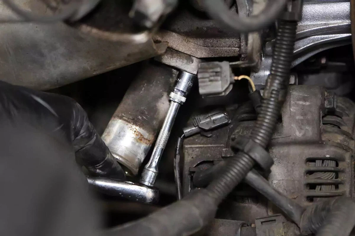 Unbolting the water neck with a socket wrench.