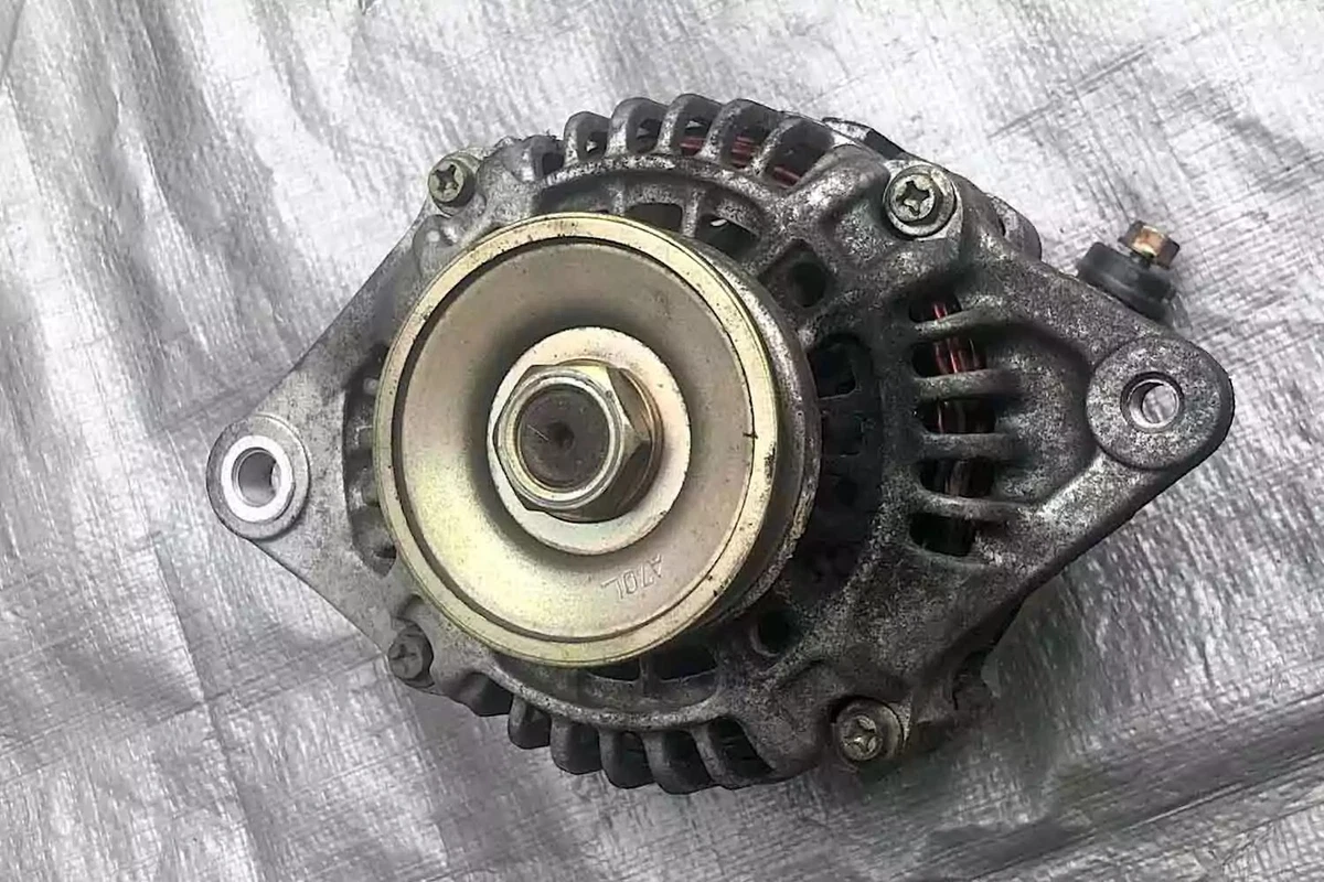 A used OEM alternator for the 1990-1993 Mazda Miata, displayed on a silver tarp.