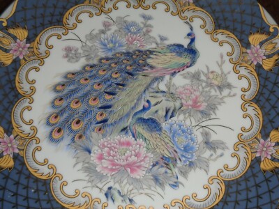 Orientalischer Teller zeigt eine Blumenszene mit einem Pfau auf grauem Hintergrund