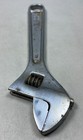 Silver 6-inch adjustable crescent wrench with worn handle, visible screw and spring tension, made in USA.