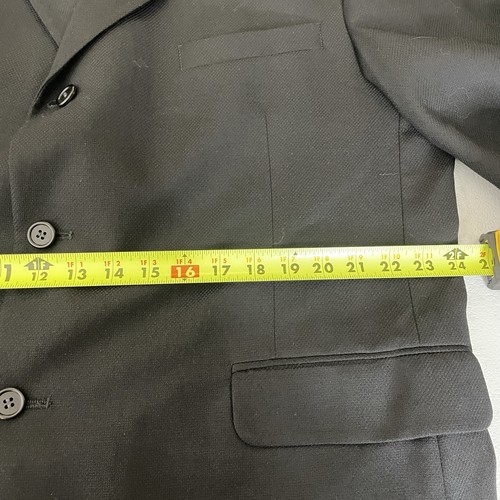 Black solid three-button blazer jacket with notch lapels, front pockets, and yellow measuring tape across the chest.
