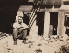 1930s Man Sitting Outside Wooden Structure Rustic Building Candid Portrait Scene