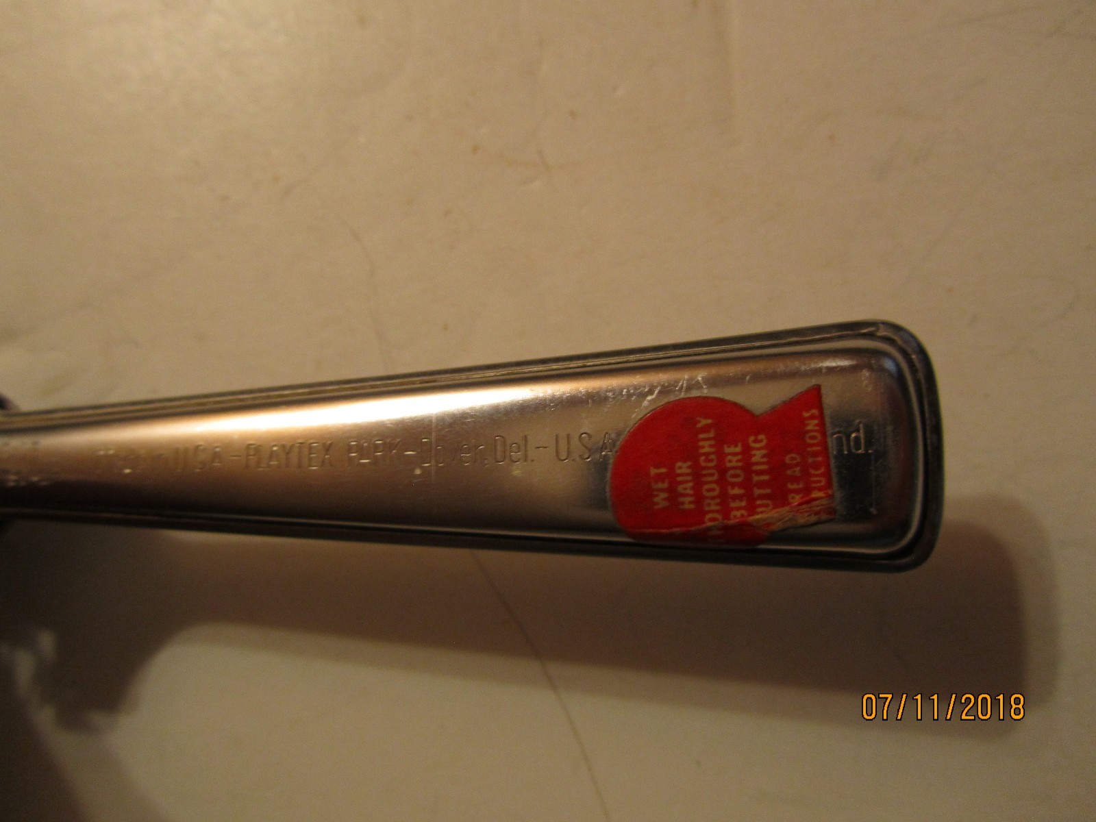 Silver Playtex hair cutter with red “Made in U.S.A.” label and black handle featuring visible branding and text.