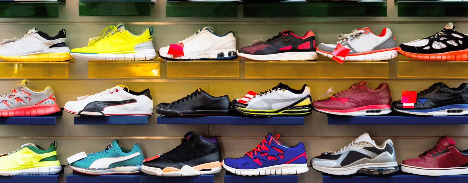 Verschiedene Sneaker-Arten auf Regalbrettern, zu sehen sind Sportschuhe, Low-Tops, High-Tops und modische Sneaker in unterschiedlichen Farben und Designs.