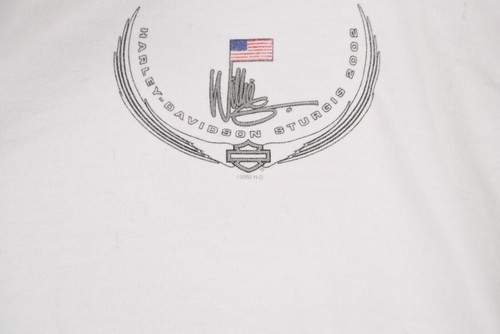 White vintage Harley-Davidson Sturgis 2002 polo shirt with black embroidered winged logo and red, white, and blue USA flag.