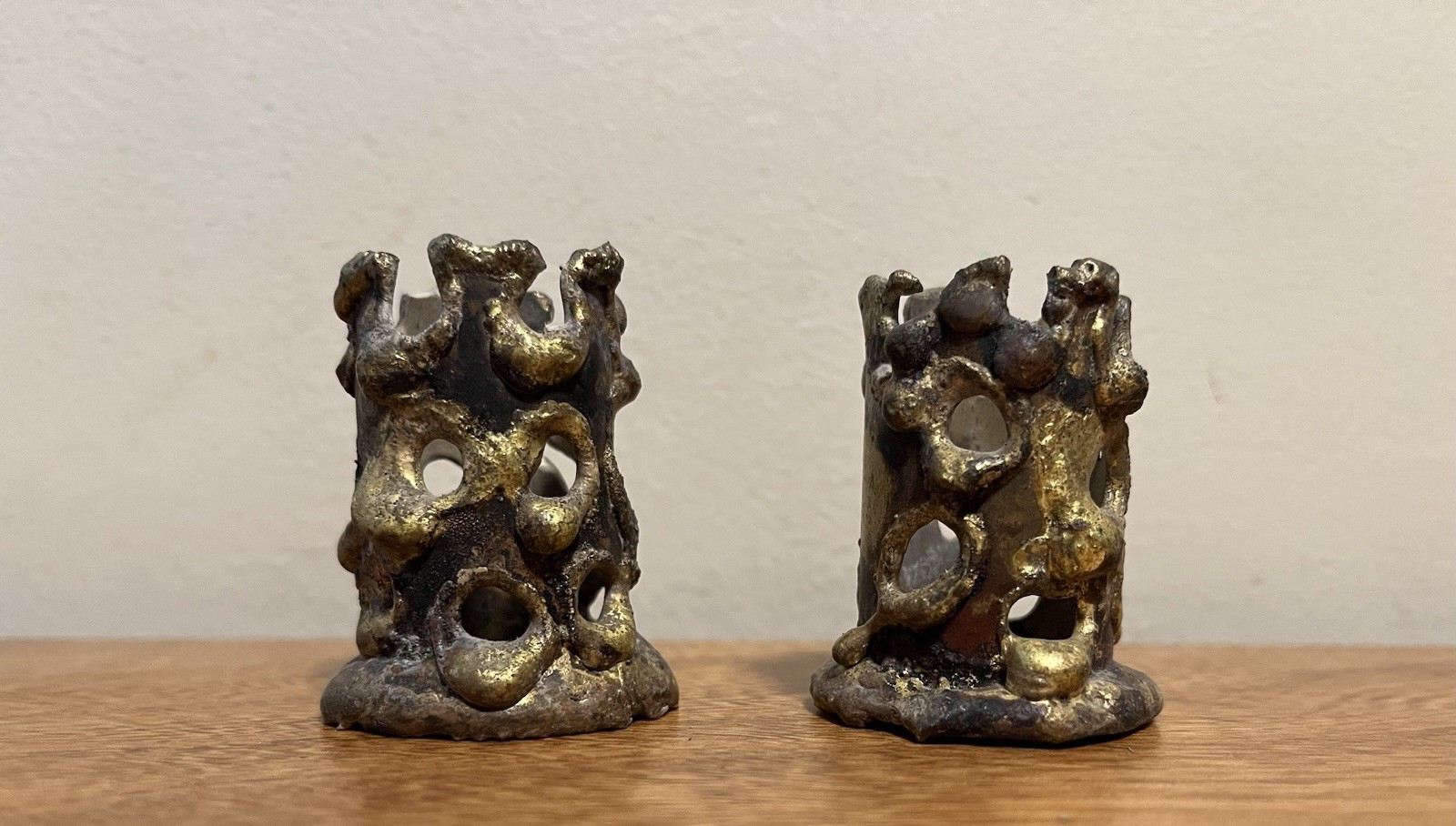 Two matching metal candle holders with an angular, faceted brutalist design.