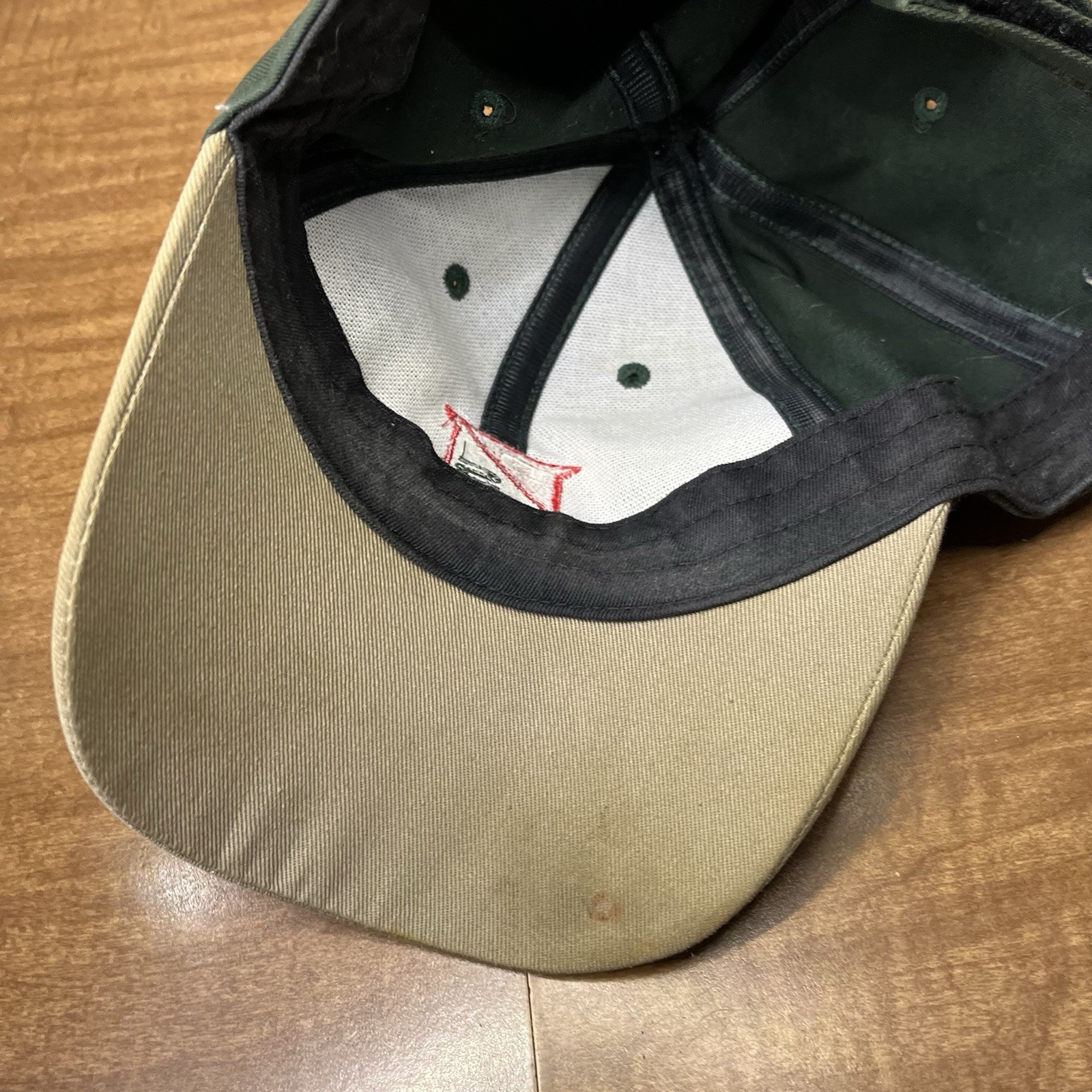 Green vintage Dairyland seed hat with tan fabric, black stitching, and red arrow graphic on the front panel.