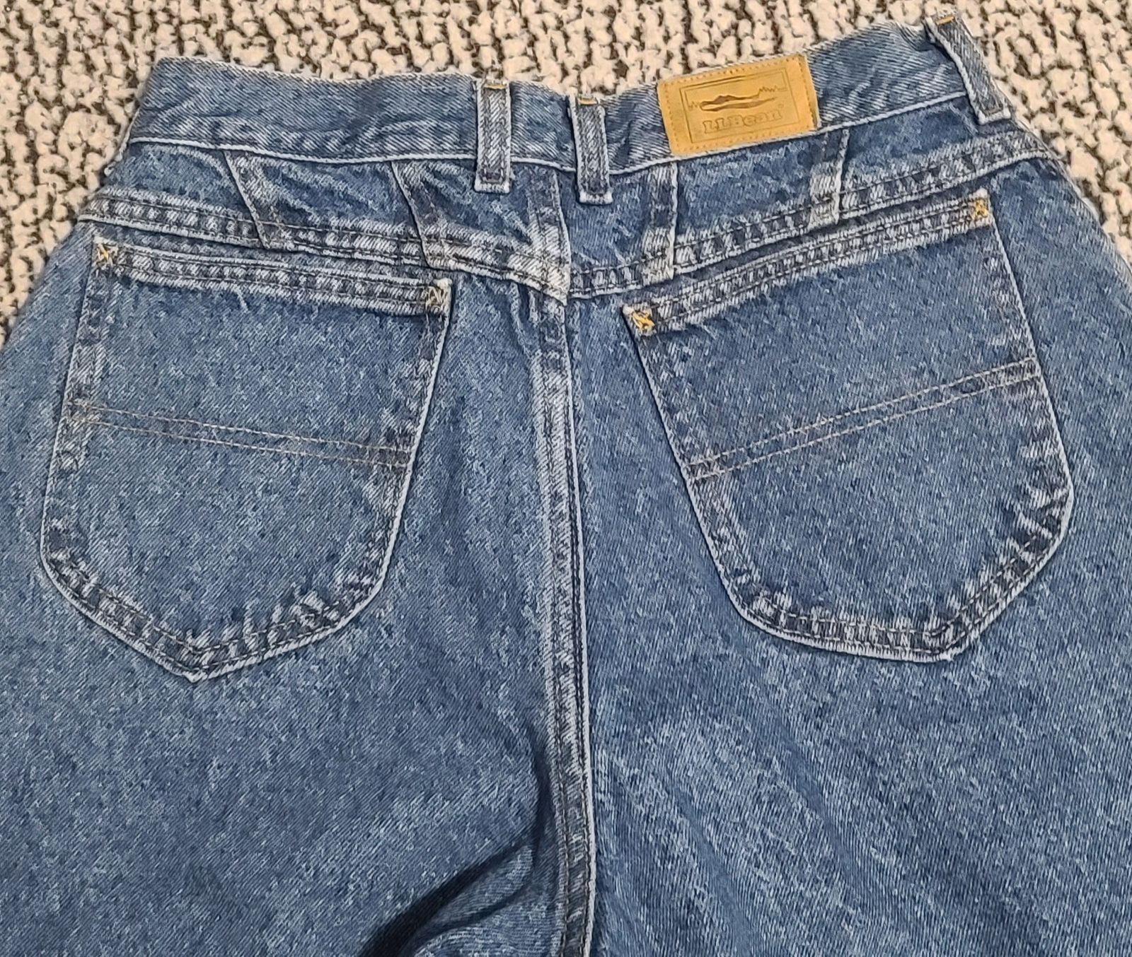 Blue high-waisted L.L.Bean mom jeans with two back pockets, brown leather patch on waistband, and yellow “L.L.Bean” tag.
