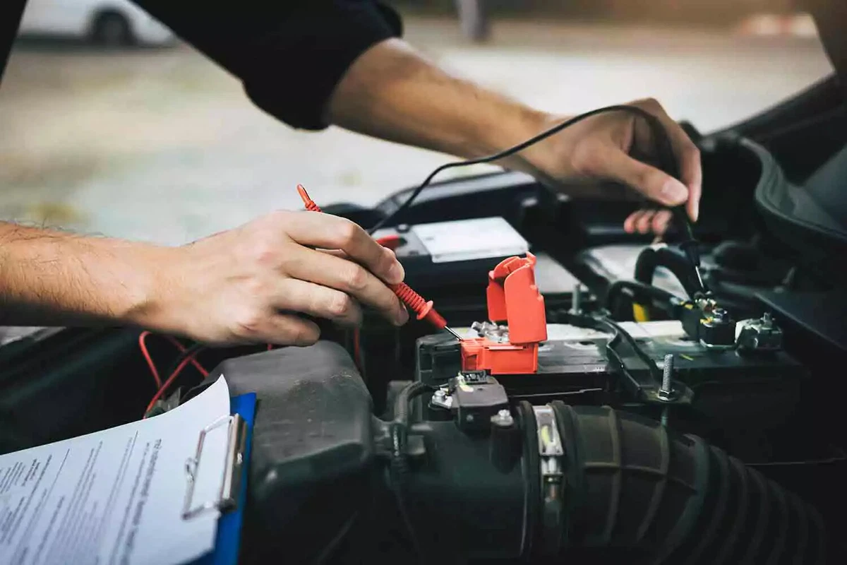 Using a handheld battery tester to test a car battery's voltage.