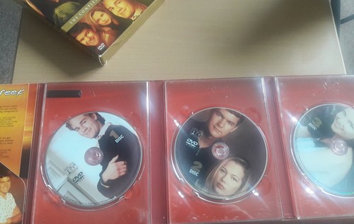 Three Dawsons Creek first-season DVDs with character close-ups and sunny beach scene on red and black spines.
