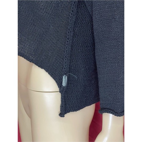 Black asymmetric crop sweater with long sleeves and front pockets, displayed on a white mannequin torso.