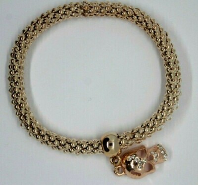 BRACELET  EXTENSIBLE ; DORE façon or ROSE; CHARM tête de mort avec strass.