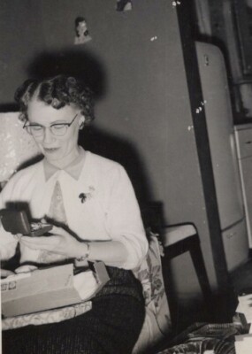 Woman with Glasses Looking at Object on Couch Cozy Scene 1956