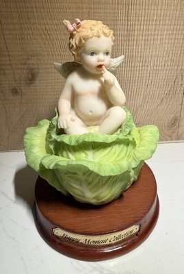 Vintage ''Happy Moment Collection'' features a cherub seated inside a cabbage.