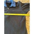 Black quarter zip fleece pullover with light blue collar, laid flat on surface with measuring tape.