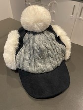 knitted winter hat with a visor and white faux fur ear muffs and pom-pom New