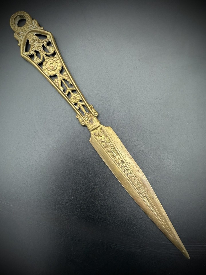 A sculpted brass letter opener with a figural lady handle — equal parts functional tool and Victorian-era desk sculpture.