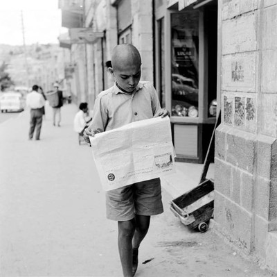 Boy reads a paper as he walks along a street in Amman 1950s OLD PHOTO