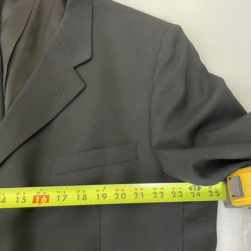 Black solid three-button blazer jacket with notch lapels, front flap pockets, and yellow measuring tape across the chest.