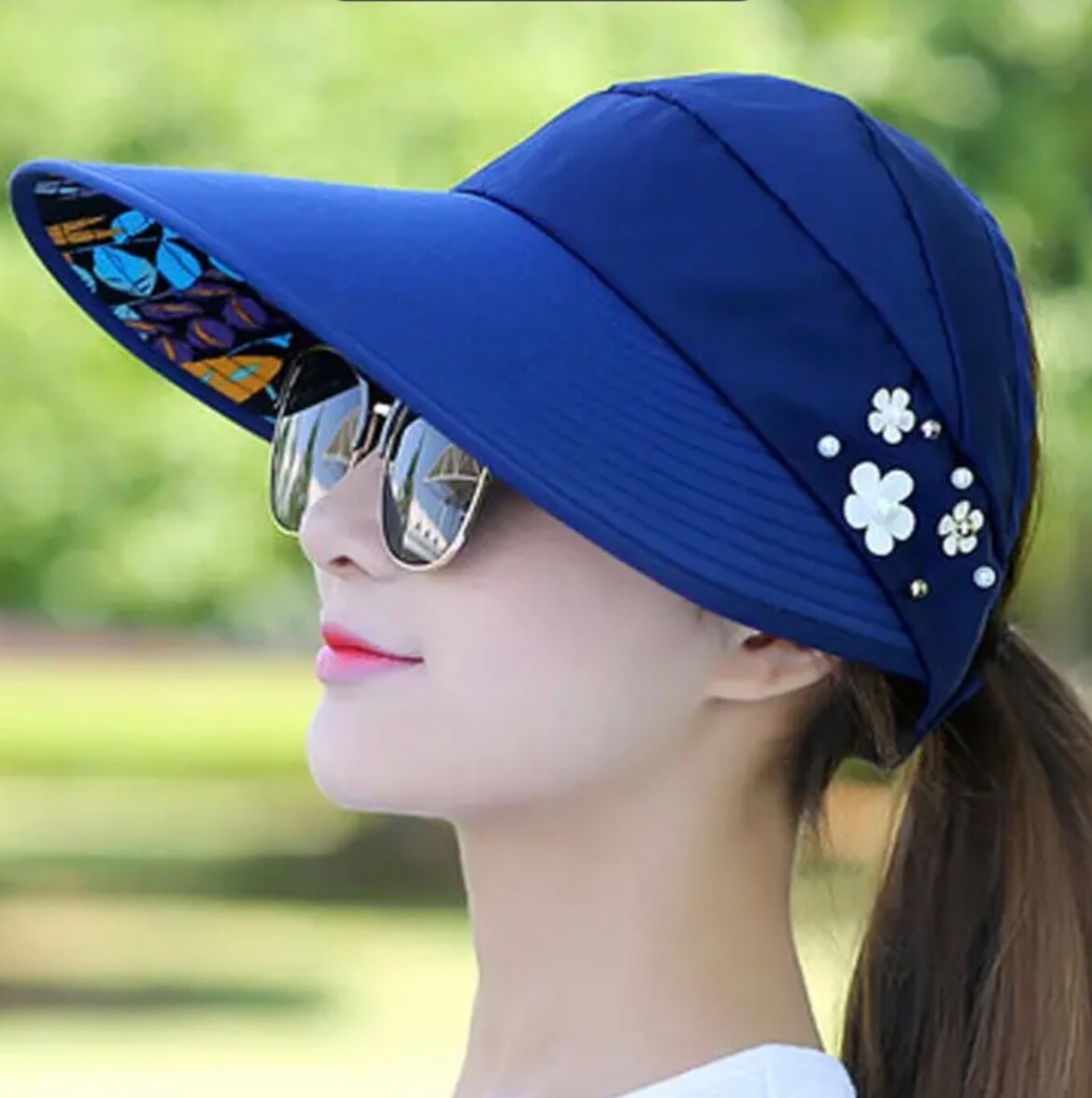 Cappello da sole tesa larga. Finte perle sul lato. Fodera a rete. Apertura coda di pony. Blu navy