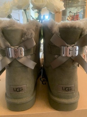 UGG Mini Bailey Bow Metal Graphic Logo Olive Suede Sheepskin Boots NIB Sz 11