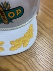 White vintage trucker hat with green and yellow Coop Seed logo, featuring embroidered cornfields and trees on the front panel.