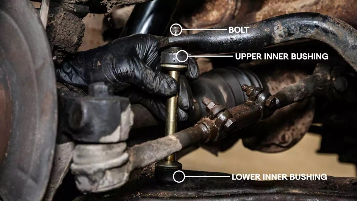 With the spacer, upper inner bushing, and washer on the bolt, a mechanic slides the bolt through the sway bar hole.