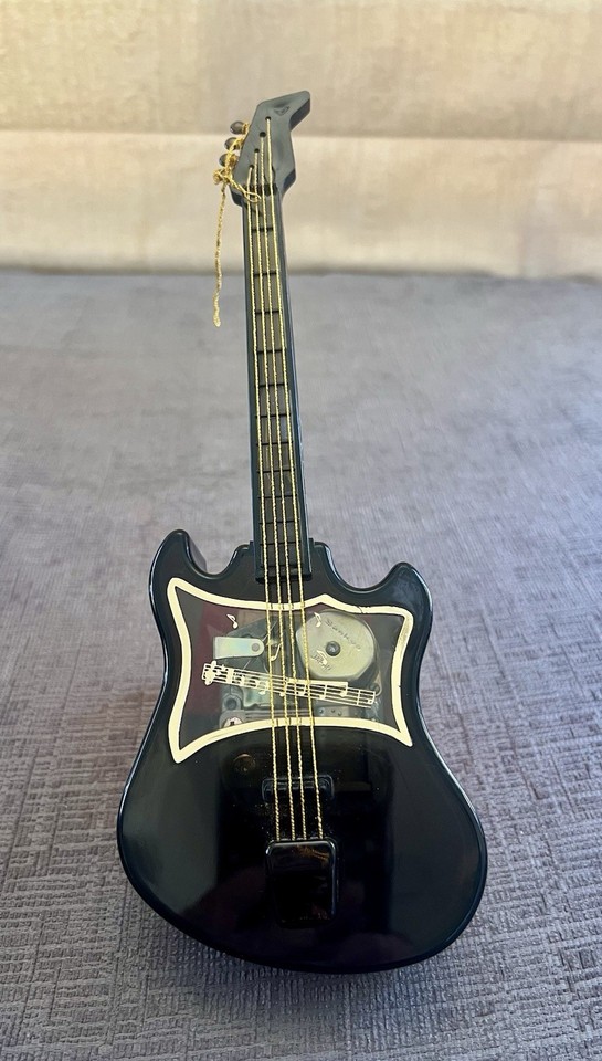 A clear acrylic guitar-shaped music box by Sankyo playing 'Love Me Tender' — a quirky, fully functional vintage novelty.