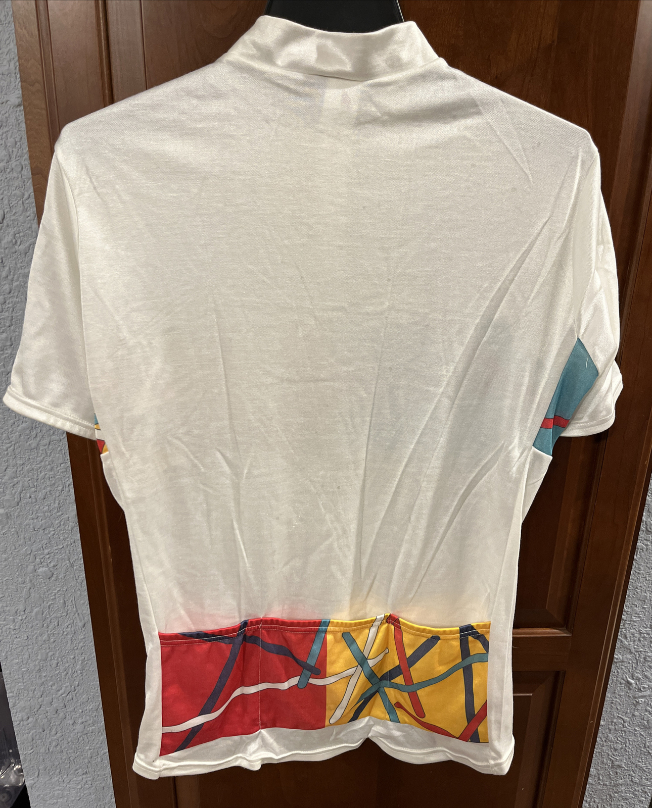 White vintage Frank Shorter sports wear cycling jersey with red, blue, and yellow abstract geometric design on back, made in USA.