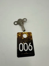 A vintage metal clock winding key with 'INDIA' stamped on it.