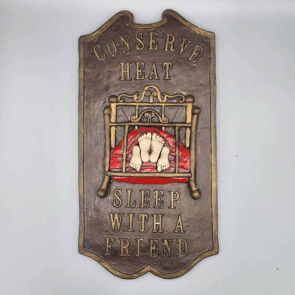 A chunky 15" vintage ceramic wall sign with a cheeky 'Conserve Heat Sleep With a Friend' slogan — genuinely funny, genuinely old, genuinely one-of-a-kind wall art.