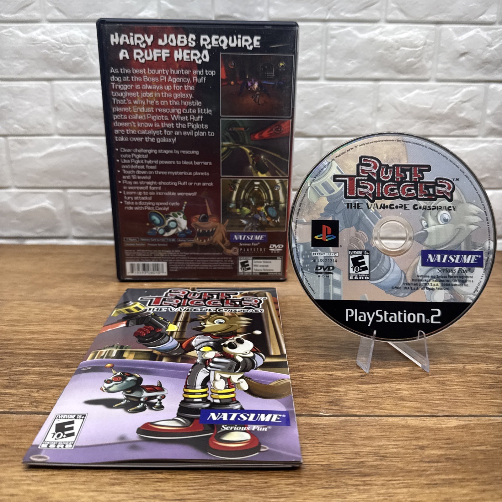 Ruff Trigger: The Vanocore Conspiracy PS2 case, manual, and disc with cartoon characters and glowing blue-orange armor.