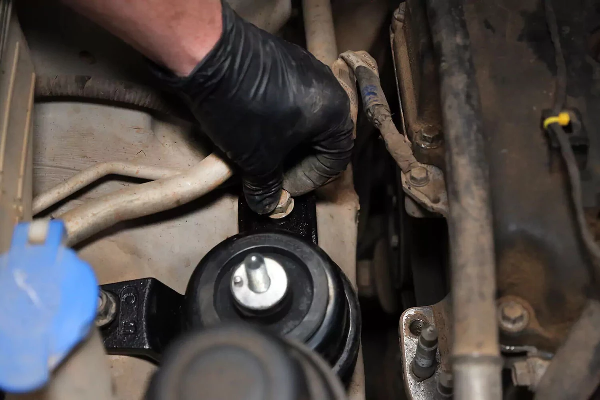 Mechanic threading a bolt into the new motor mount.
