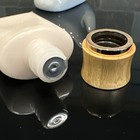 Clear plastic bottle of Tarte Amazonian Clay Foundation with silver cap, topped with a polished wooden cap on black surface.