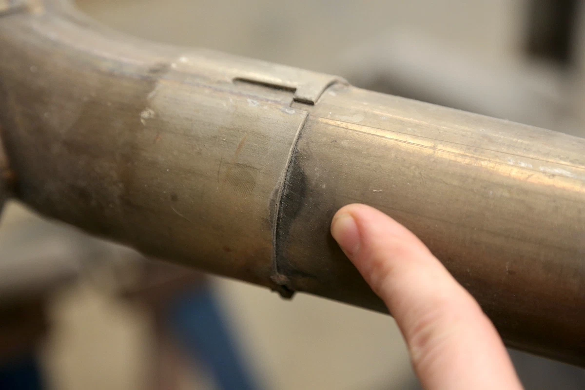 The soot mark indicates an exhaust leak at the junction of two pipes.