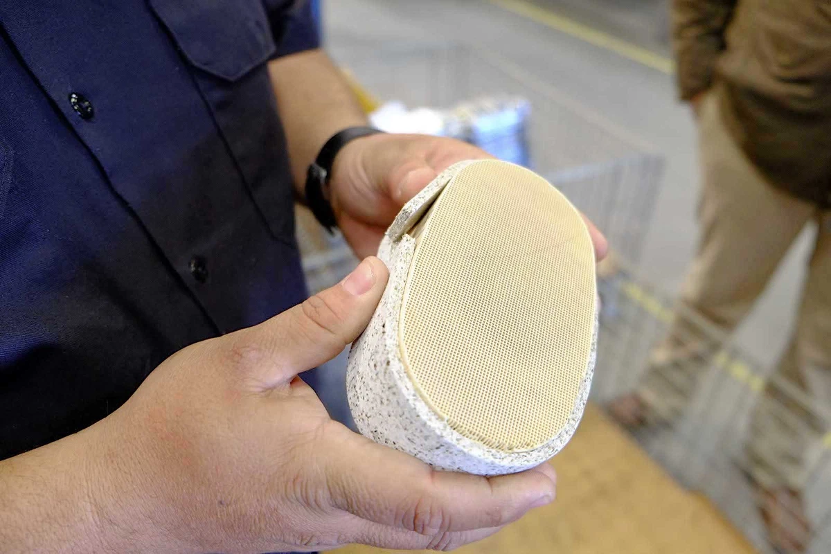 A mechanic holding a catalytic converter honeycomb.