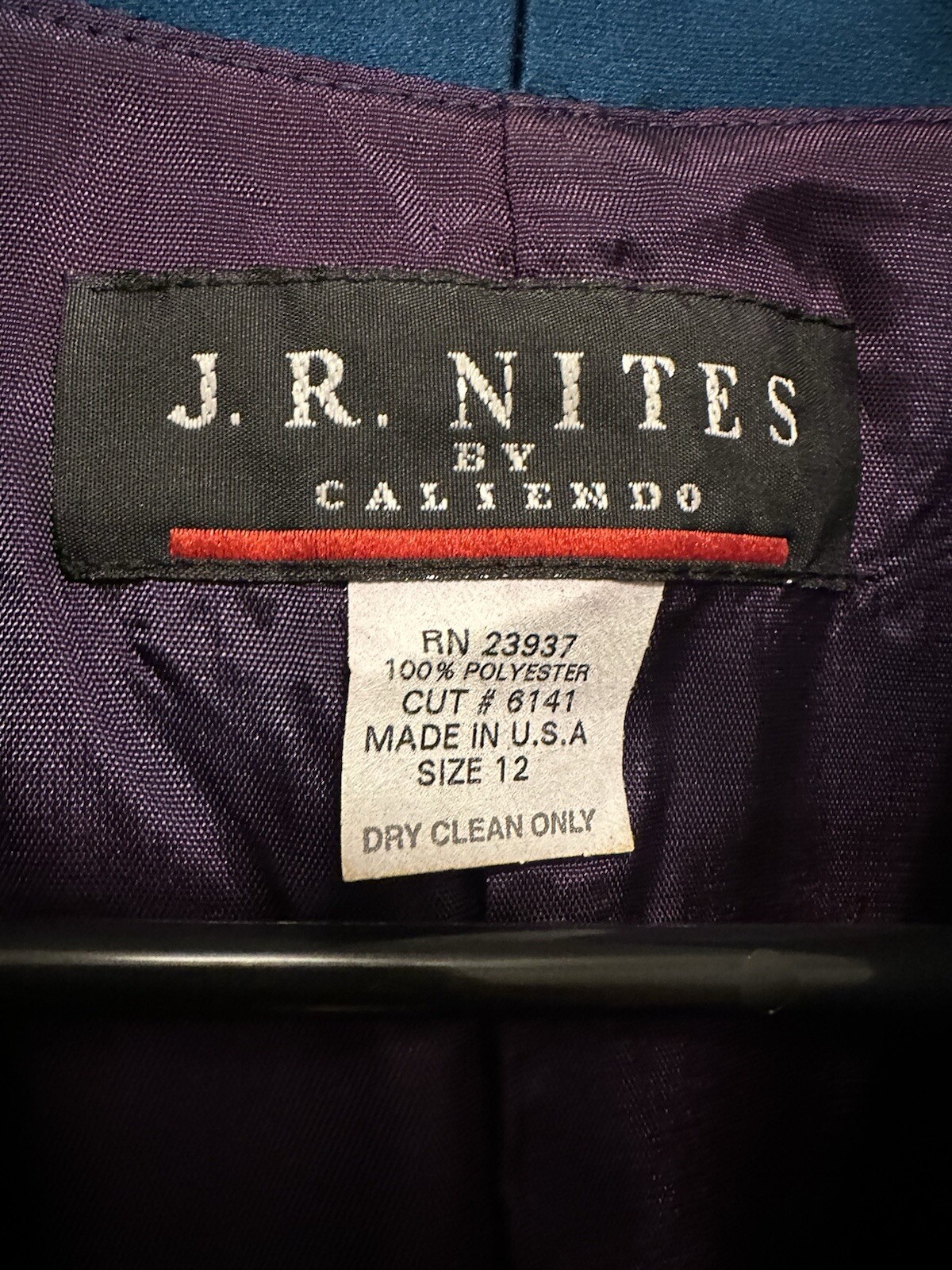 White fabric label on dark purple garment with red “J.R. Nites by Caliendo” text, product number RN23937, size 12.