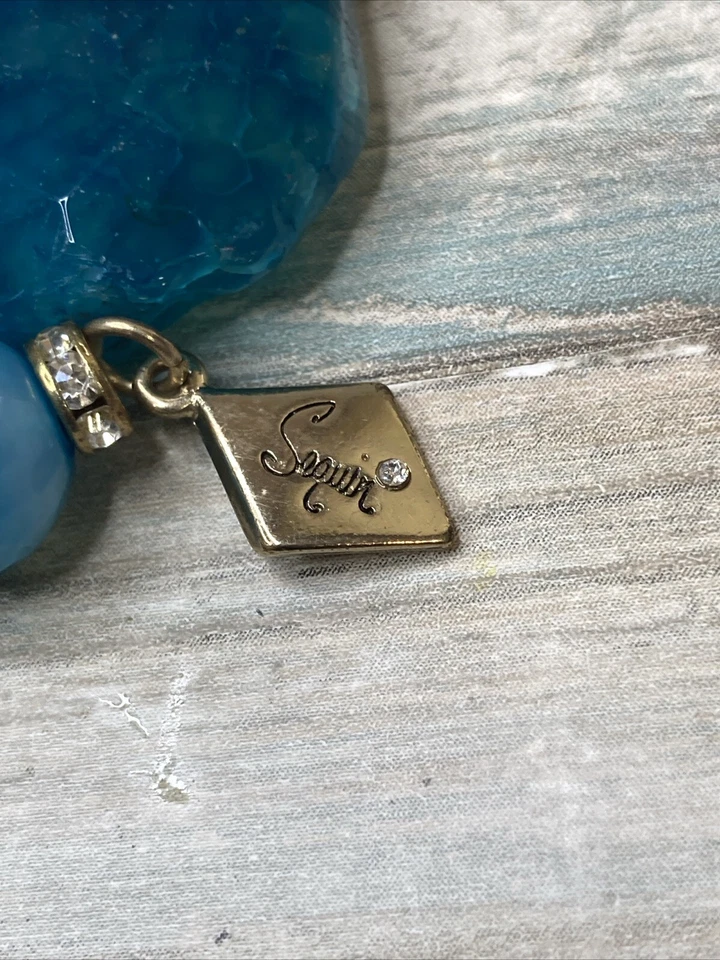 Pulsera elástica ágata azul de lentejuelas de diseñador. Diamantes de imitación con logotipo en tono dorado Foto 4 de 4