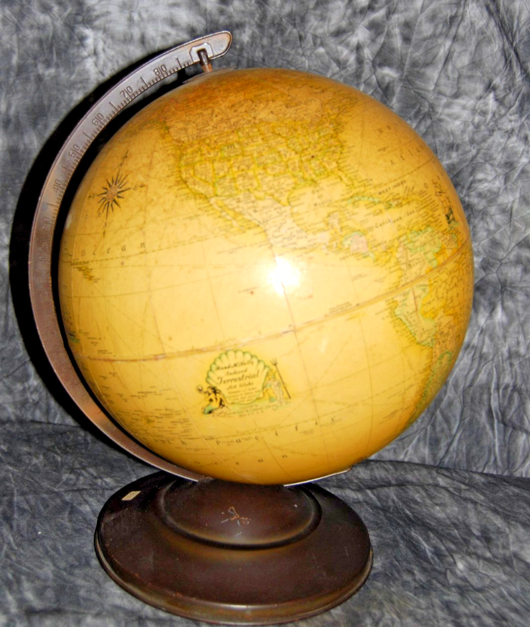A vintage world globe on a wood and metal stand showing pre-war country names and colors.