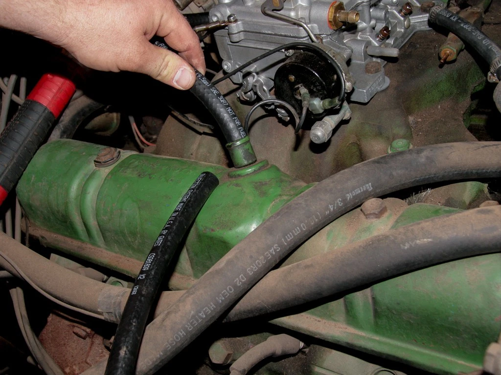 A man installing a Positive Crankcase Ventilation PCV valve on a 1963 Buick Nailhead V-8 engine