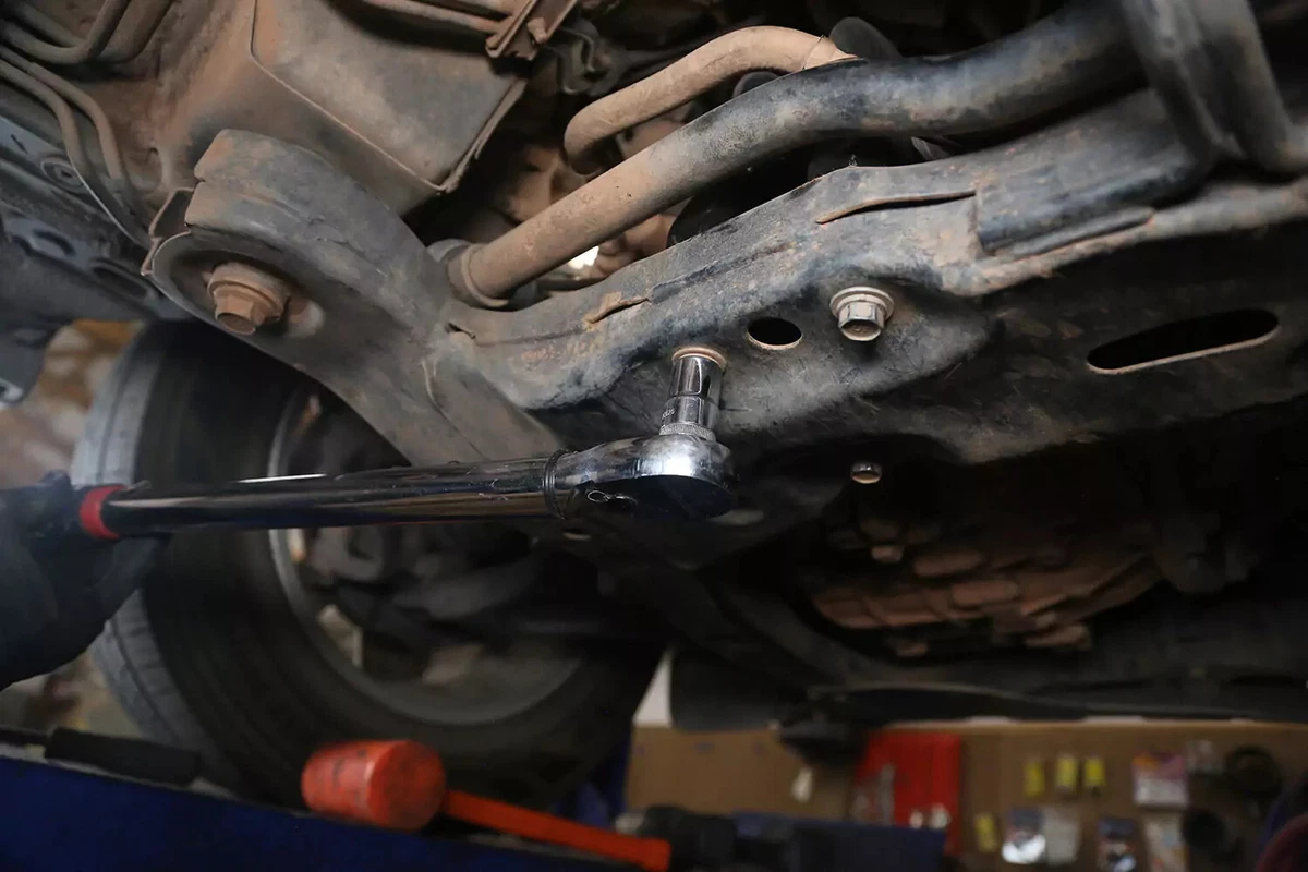 A torque wrench is used to tighten the bolts of a transmission mount.