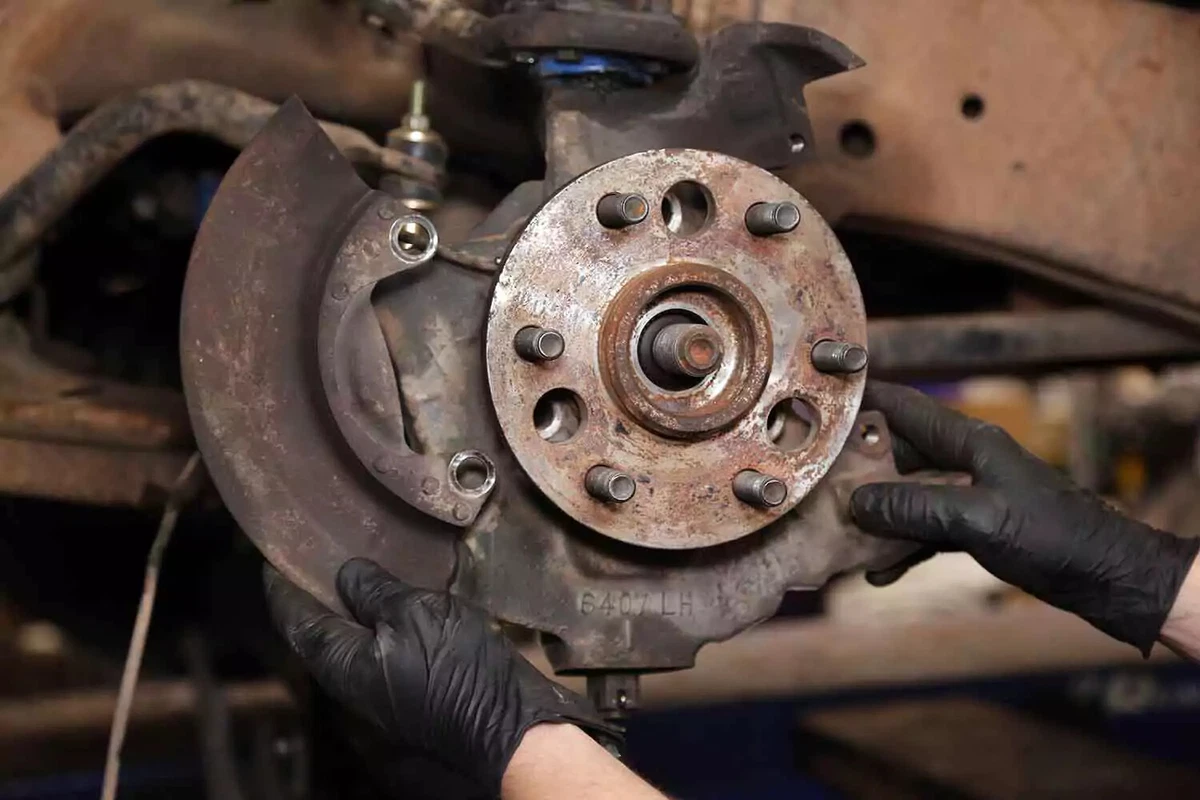 A mechanic removes the splash shield.