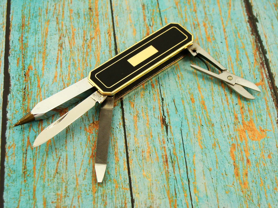 A gold-finished vintage Japanese multi-blade pocket knife with scissors, pen blades, and more — an ornate little gadget that feels like a prop from a spy film.
